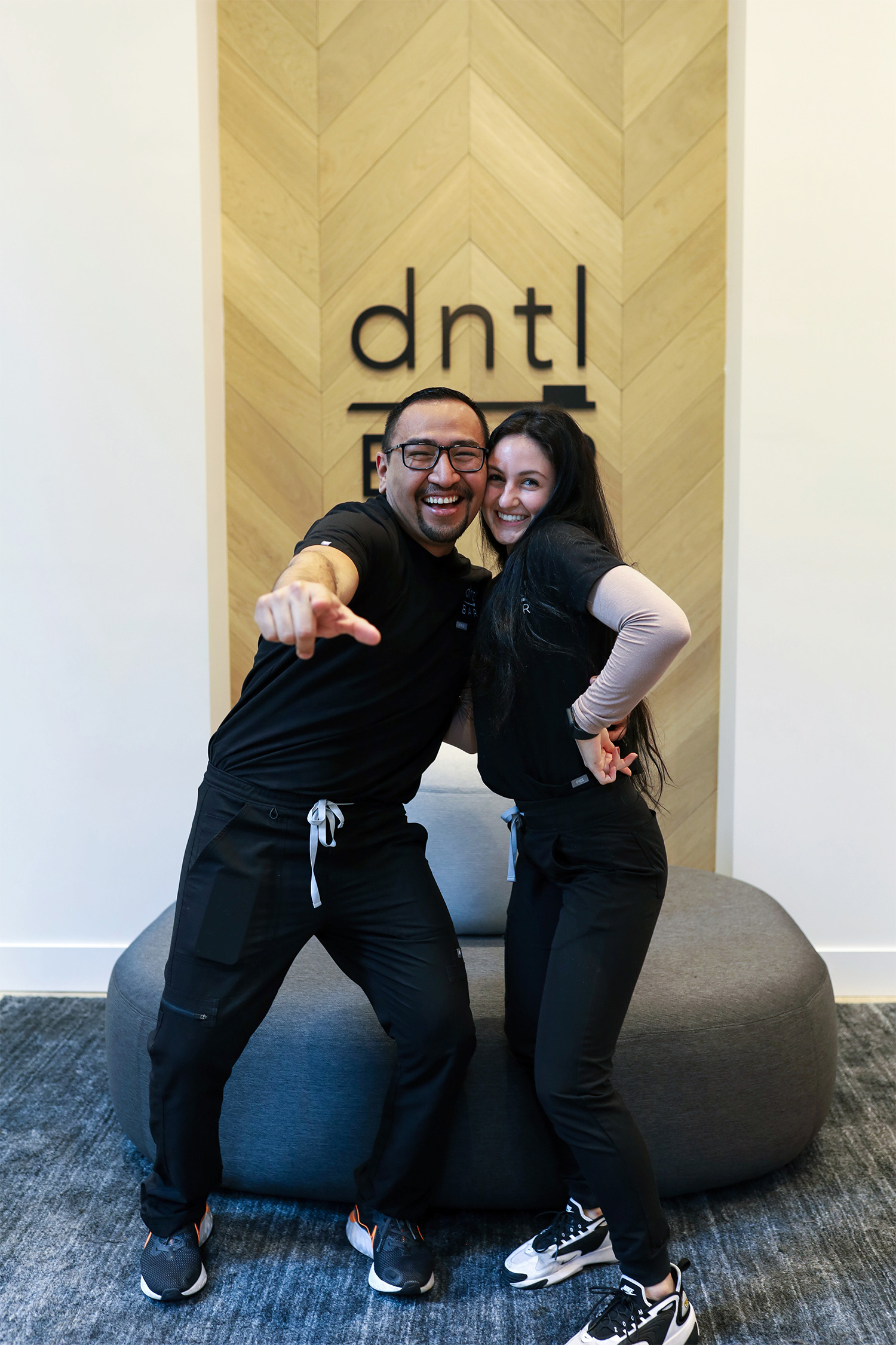 two dntl bar employees in the lobby, smiling and pointing to the camera