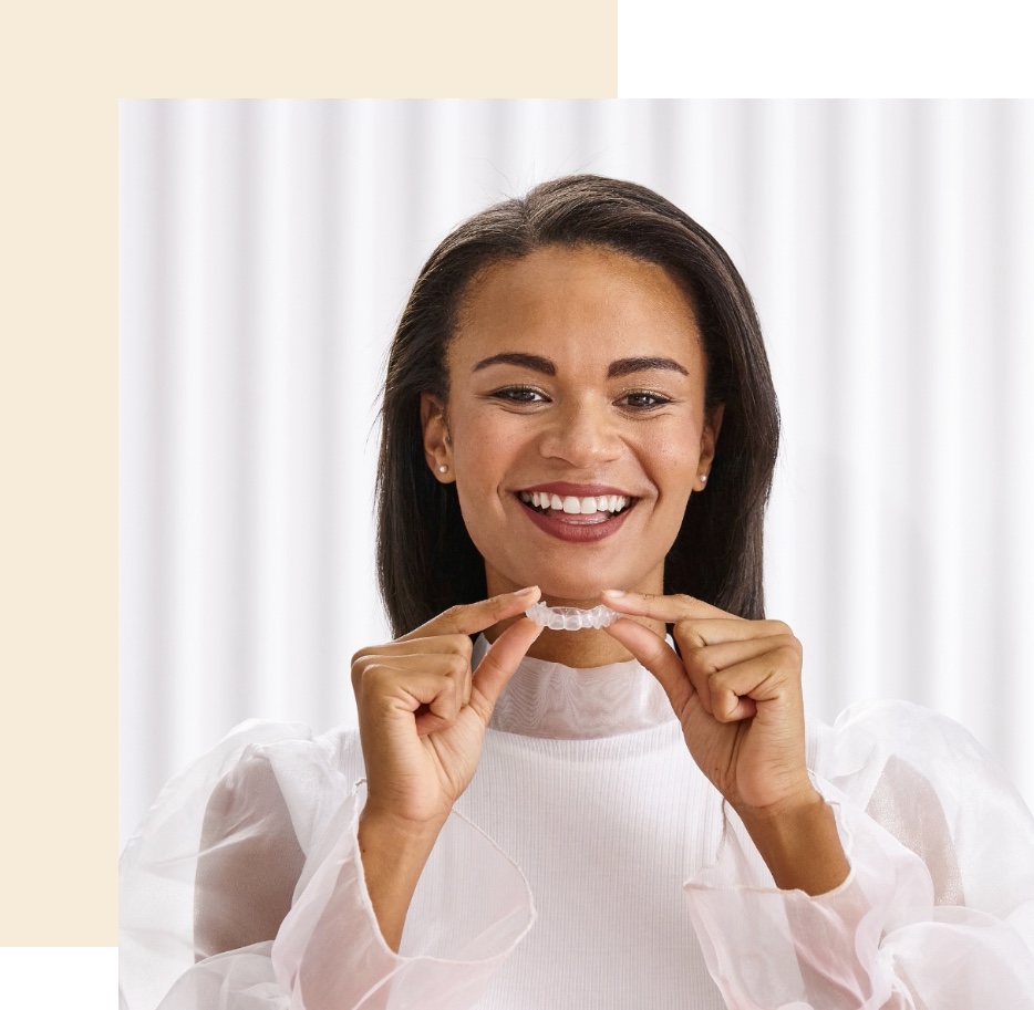 woman holds aligner and smiles